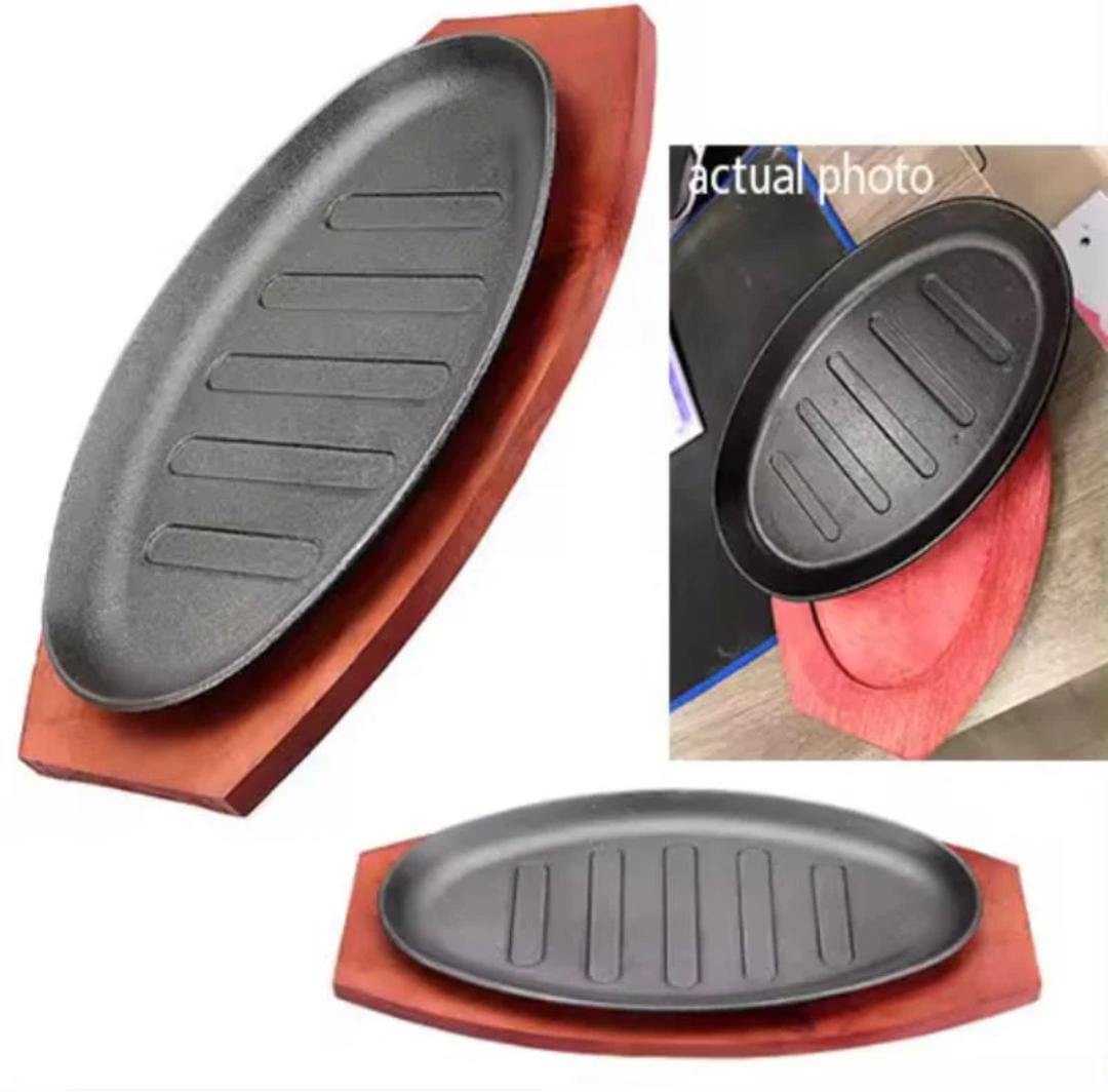 Cast iron hot sizzling plate on wooden tray