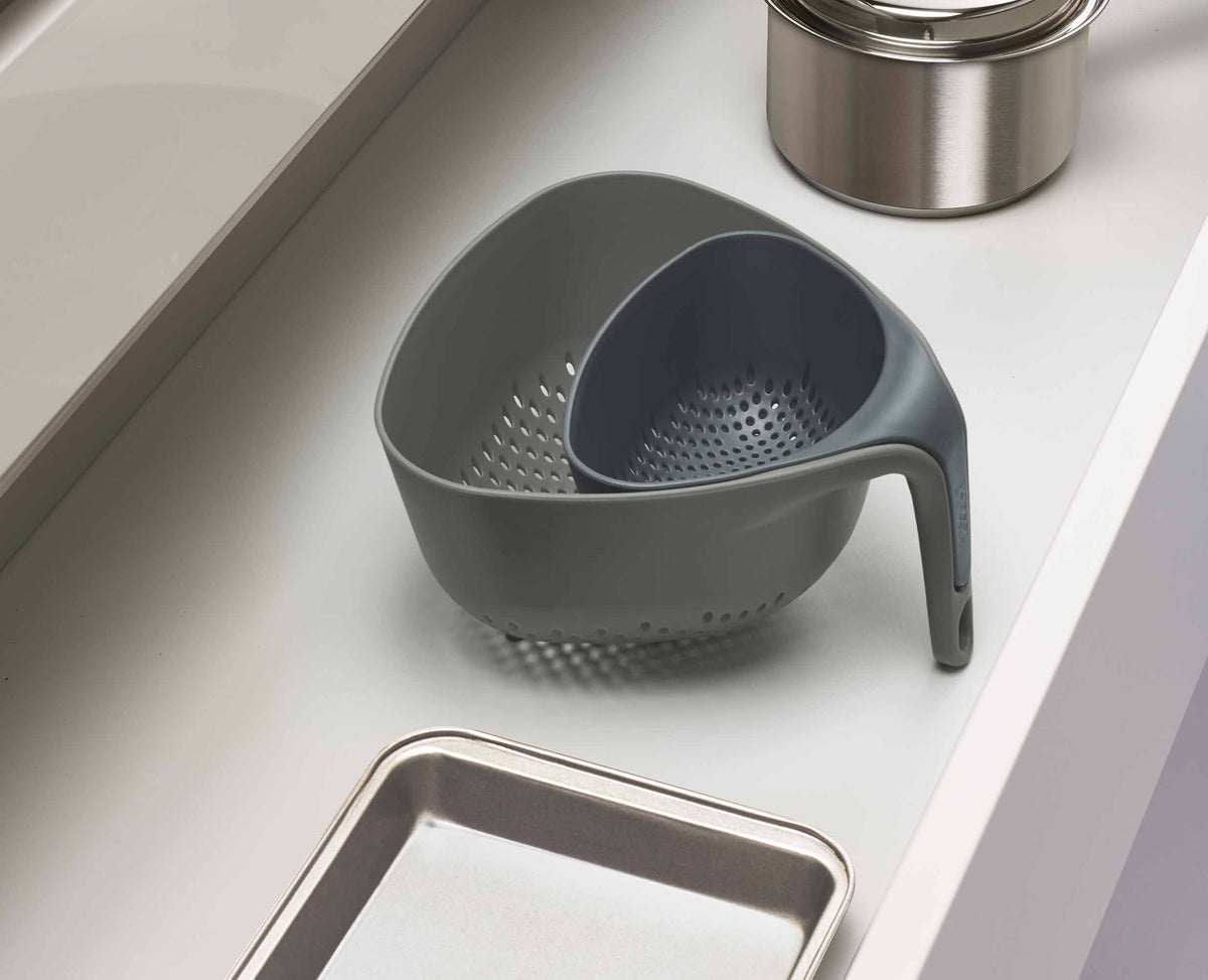 A grey Nest colander standing upright while draining food