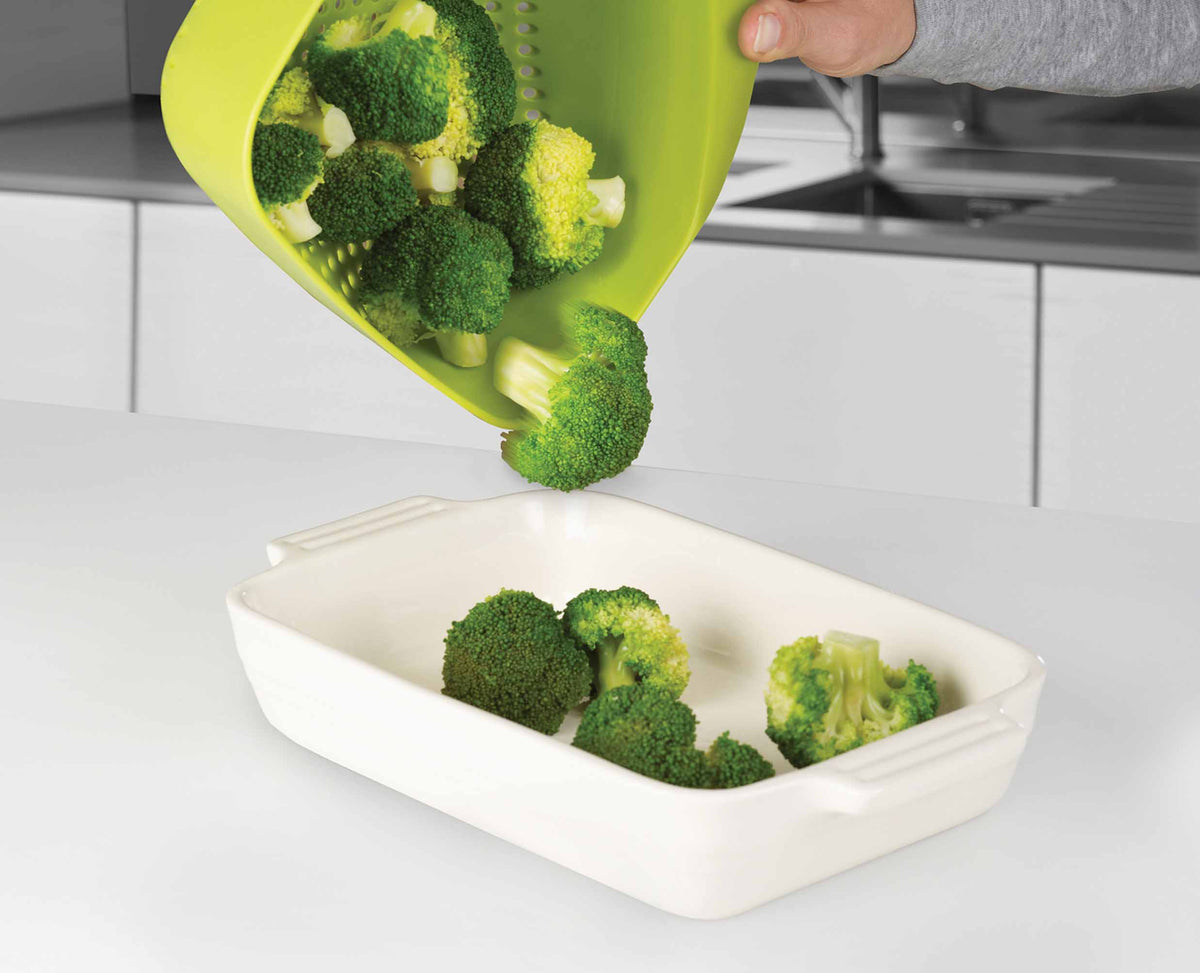 The green Joseph Joseph colander in use draining food