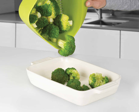 The green Joseph Joseph colander in use draining food