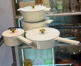 14 piece cast aluminium non-stick cookware set in cream on a cooker