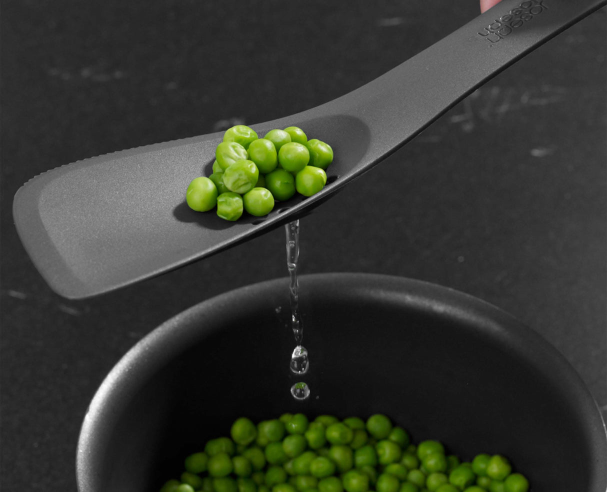 The tool being used as a turner to flip food in a frying pan.