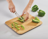 Chopped vegetables being prepared on the textured bamboo cutting surface.