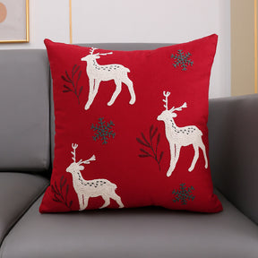 Christmas cushion cover 45x45cm, red canvas with three embroidered reindeer and snowflakes on a grey sofa