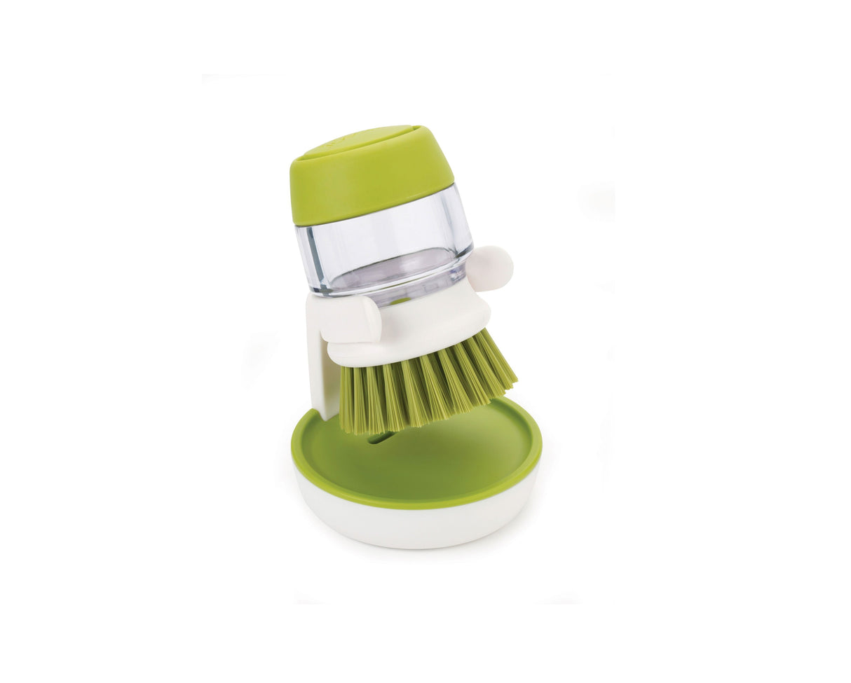 Side profile of the green Palm Scrub brush showing its soap reservoir body.